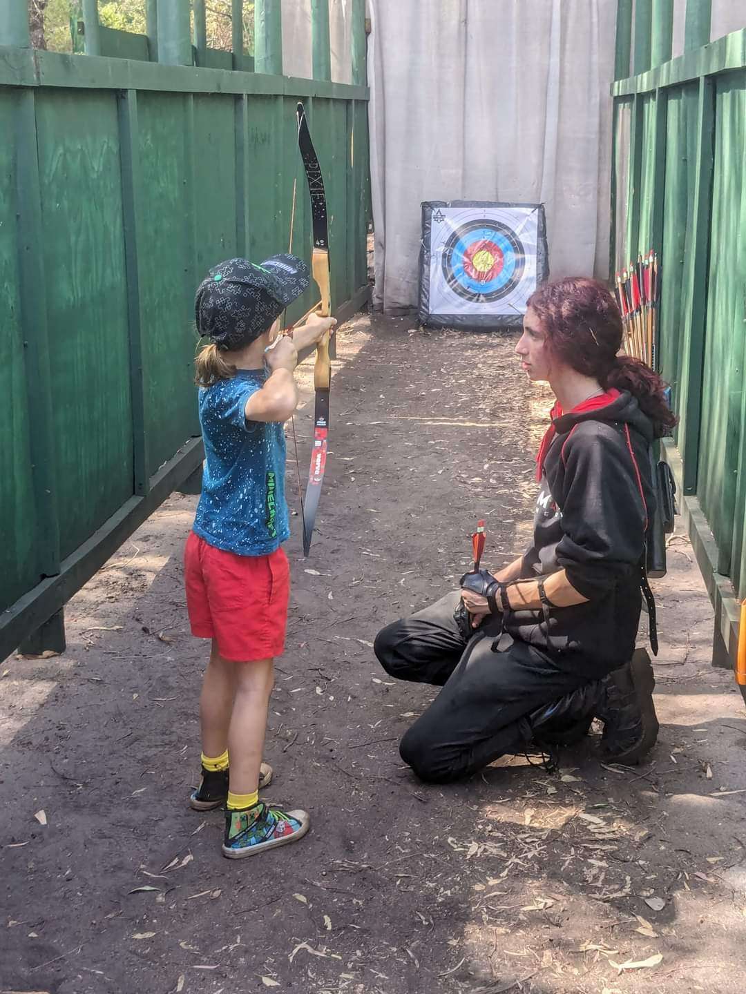 Instructor helping a young archer during a beginner outdoor archery session in Busselton.