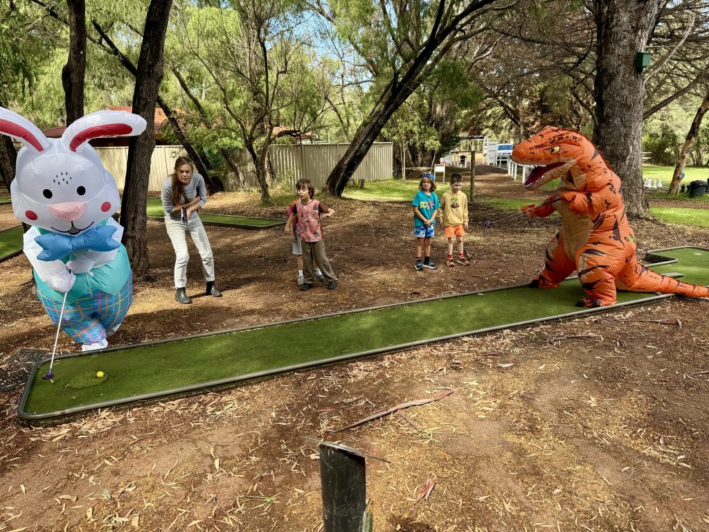 Kids playing Easter mini golf with a bunny and dinosaur mascot at Primal Archery in Busselton