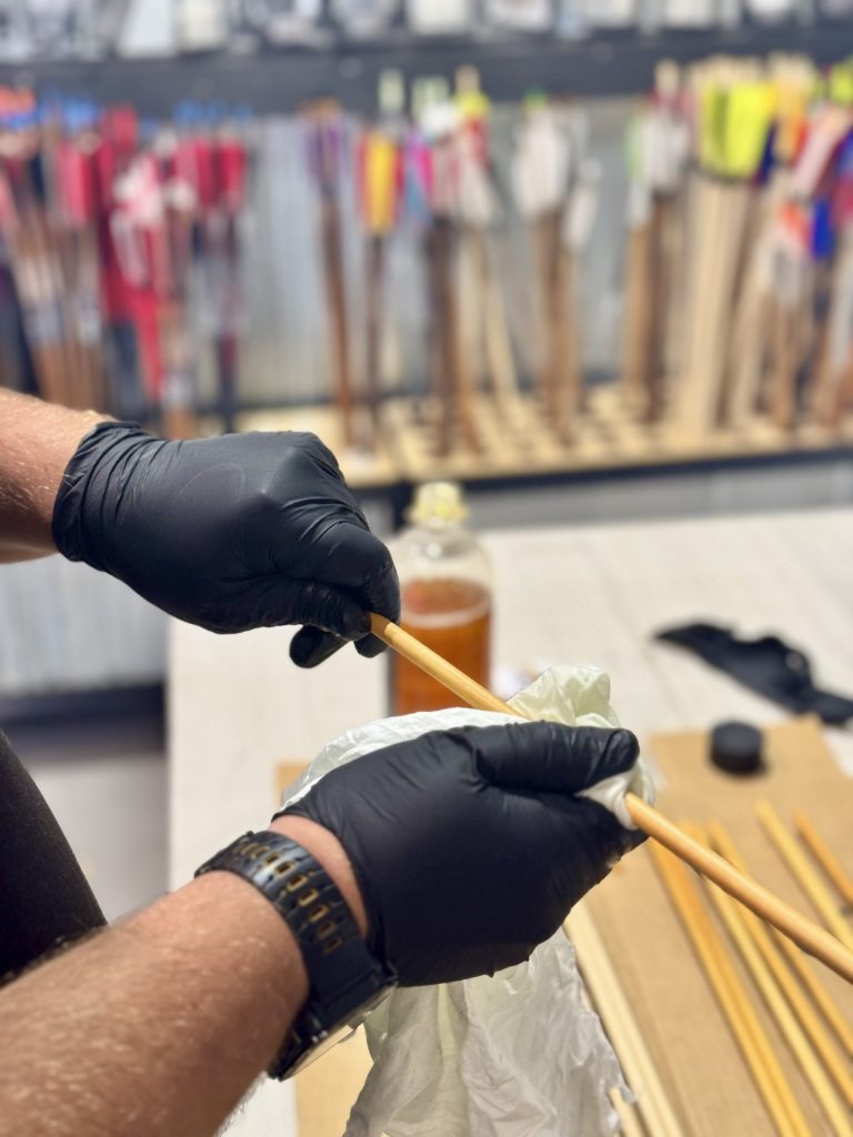 Wooden arrow shaft being finished by hand with linseed oil in our Busselton workshop
