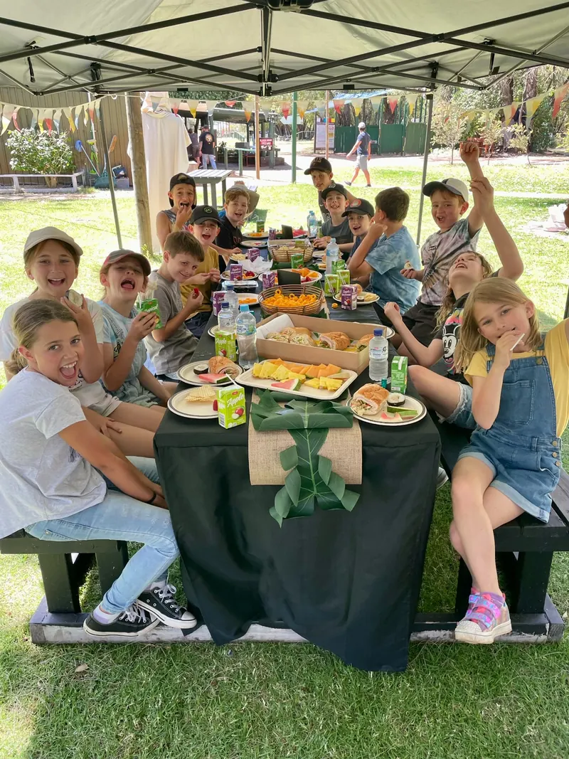 Kids around a party table under a shade tent at the park