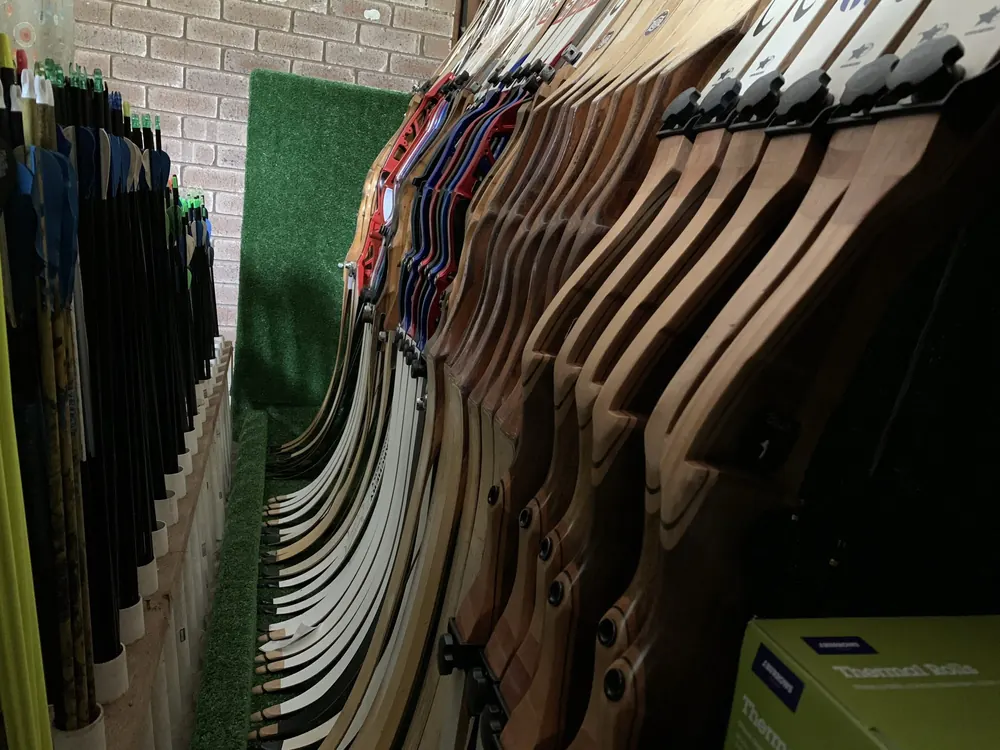 A rack of wooden recurve bows hanging in the Primal shop