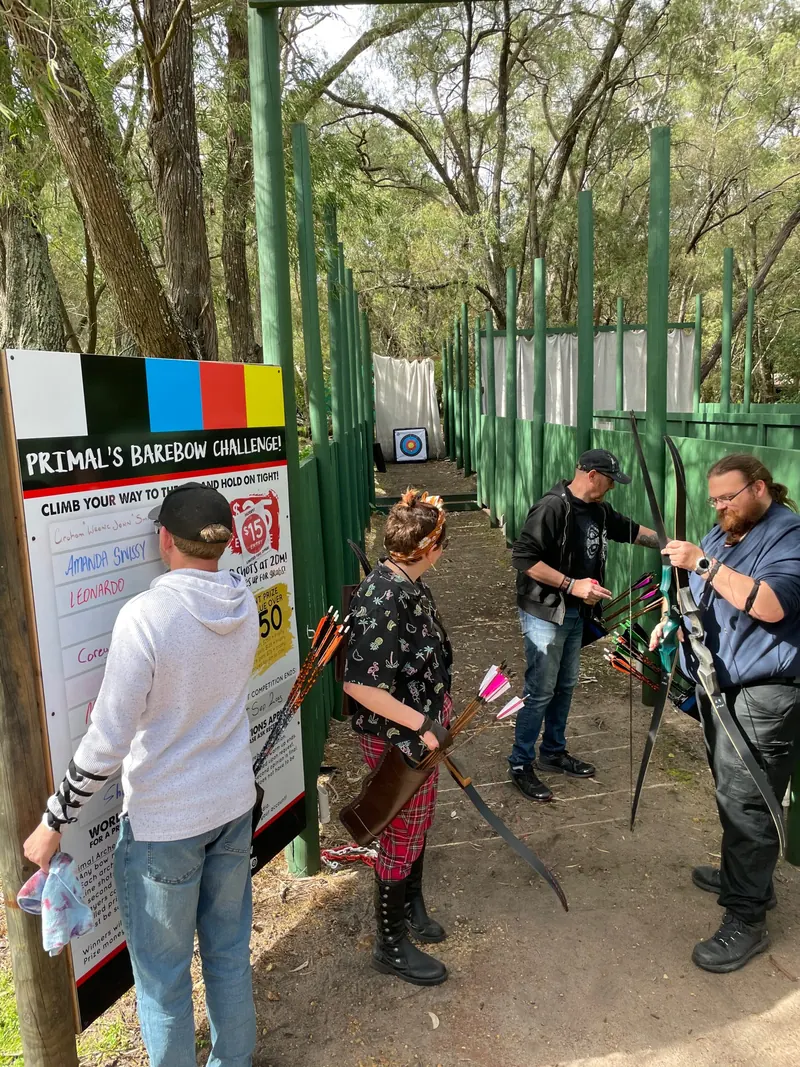 Four archers with their bows getting ready at the entrance to the fenced shooting lanes