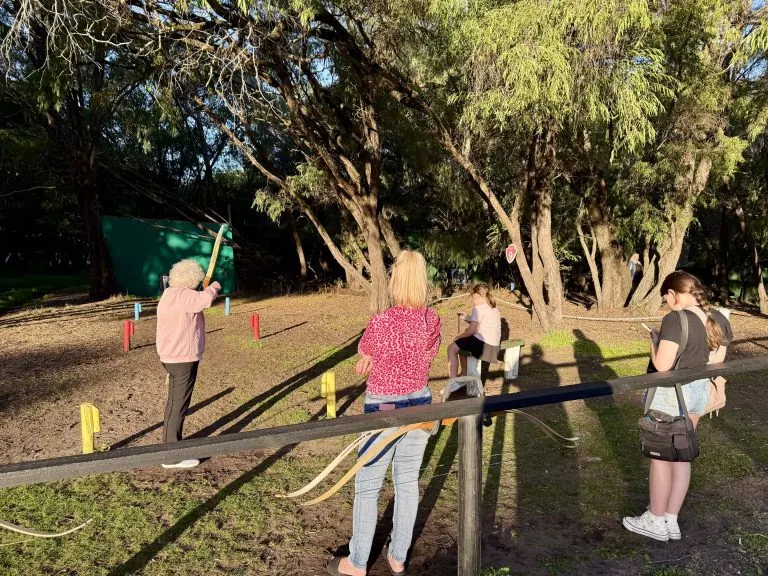 A family takes turns shooting from behind a timber rail on the course