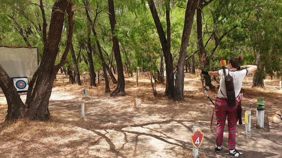 An archer shoots along a shaded bush track on The Woods course