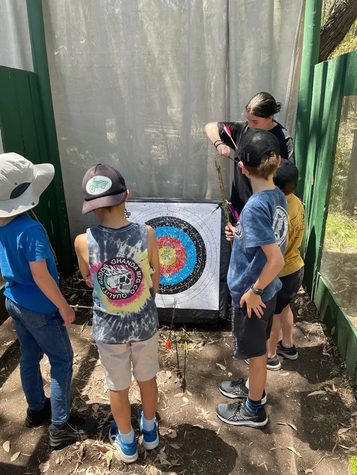 Three kids at a target collecting their arrows