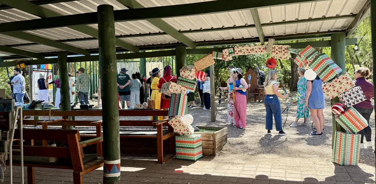 Guests with bows gather in the covered area beside timber bench seats, hung with giant wrapped presents