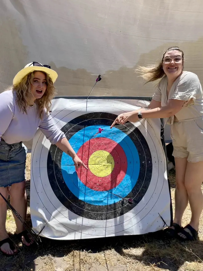 Two friends laugh and point at their arrows in a target face