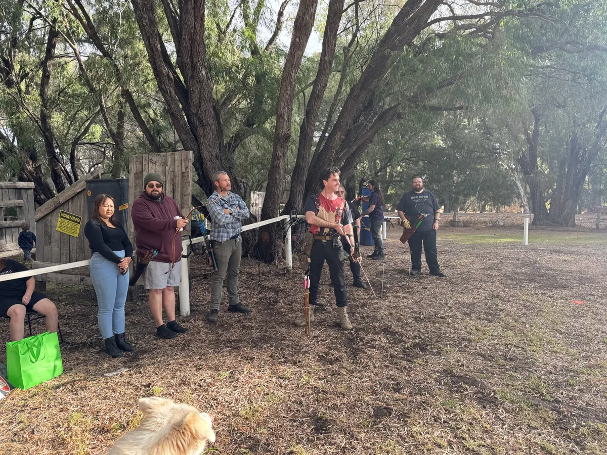 The Primal team and members standing along the range rope with their bows, a fluffy dog in the foreground